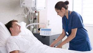 Woman in scrubs comforting patient in bed