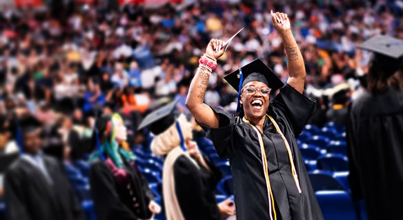 Woman in black graduate regalia cheering at graduation ceremony.