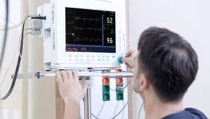 EKG technician adjusting settings on ekg machine