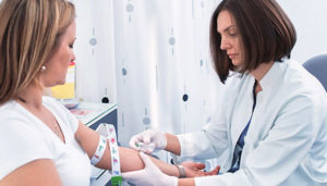 phlebotomy tech poking a female patient with a needle