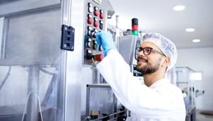 sterile processing technician pressing a button on heavy machinery.