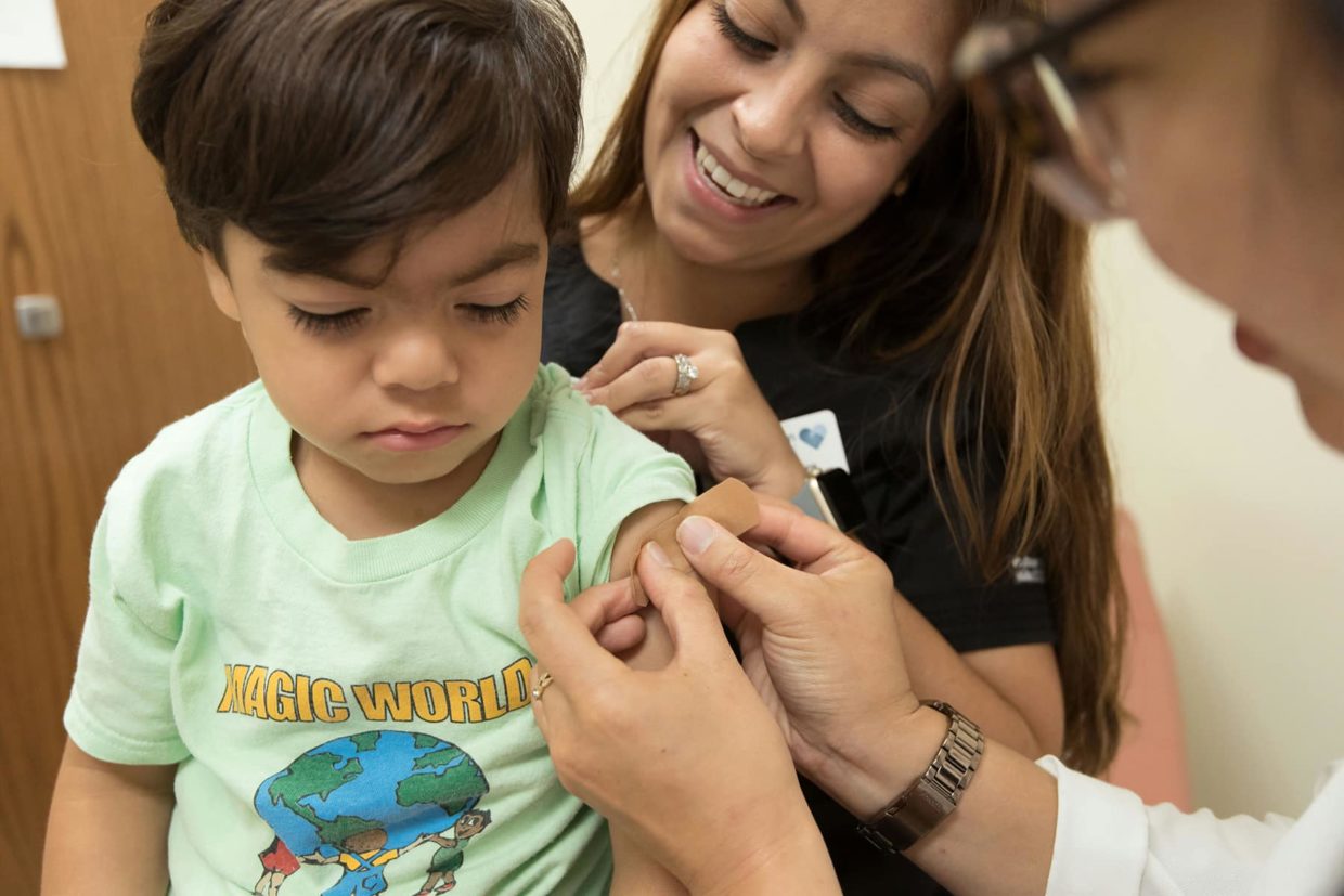 Healthcare worker placing a bandage on a child's arm.